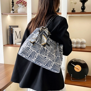 Minimalist striped tote bag with silk scarf detail and woven strap shown on model