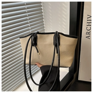 Détails du sac cabas beige tressé avec anses en cuir noir sous une lumière naturelle douce