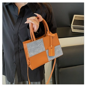 Close-up of contrast stitching detail on brown leather and grey wool square handbag