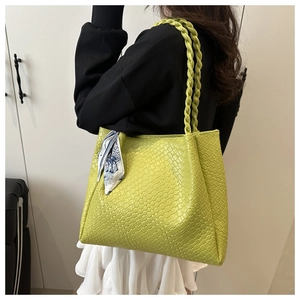 Green woven tote bag detail showing fine square texture and decorative silk scarf