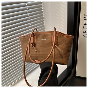 Détail d'un grand sac cabas marron tissé avec anses en cuir et logo Fashion argenté