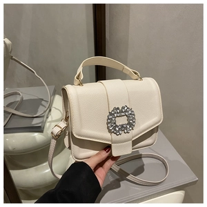 Close-up of cream textured leather handbag featuring a sparkling square crystal buckle
