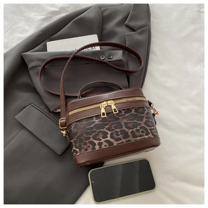 Brown leopard print crossbody bag on a grey blazer with phone for scale comparison