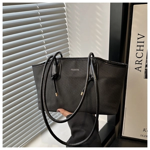 Détail d'un sac cabas en tissu noir avec texte FASHION et poignée en cuir à nœud décoratif