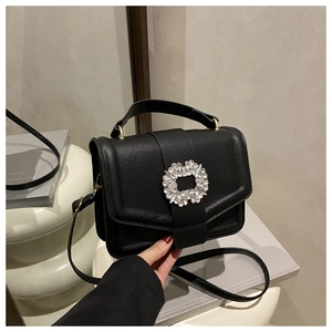 Detail of black lychee leather handbag with a sparkling crystal buckle and golden hardware