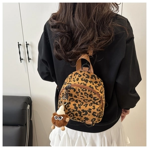 Detailed back view of a leopard print crossbody bag with plush monster charm