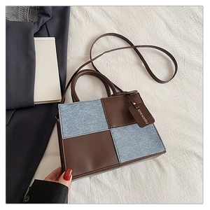 Detail view of contrast color handbag with brown leather and denim blue patchwork design