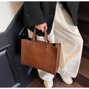Detailed shot of brown crocodile embossed tote bag with dual circular handles for commute
