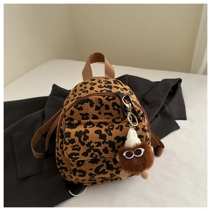 Detail of leopard print corduroy mini backpack with a cute fuzzy monster keychain charm