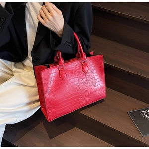 Detail of red crocodile texture tote bag showing spacious capacity and handles on stairs