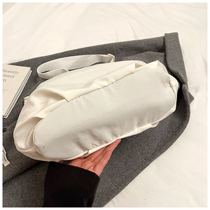 Detail view of the wide bottom design on a beige nylon crossbody bag with ample capacity
