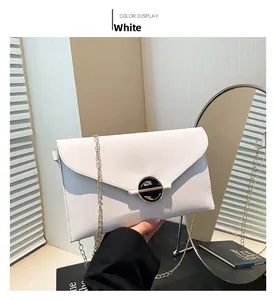 Détail d'une pochette blanche en cuir avec chaîne dorée et boucle métallique ronde