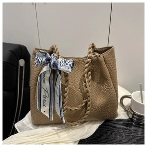 Detail of khaki woven leather tote bag with printed silk scarf and braided handle