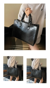 Detailed view of large black tote bag with elegant crocodile texture and sturdy top handles