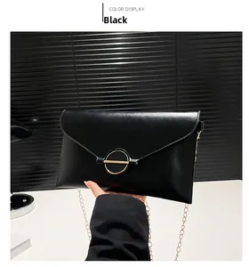 Détail de la pochette enveloppe en PU noir avec boucle dorée et bandoulière chaîne