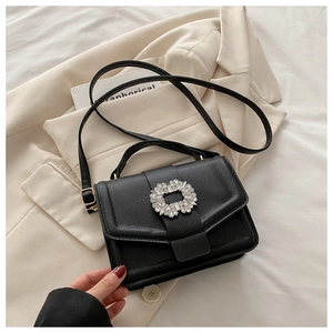Detail of black lychee leather crossbody bag with sparkling rhinestone wreath buckle closure