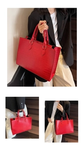 Close-up of red crocodile pattern tote bag with polished metal rings and reinforced handles