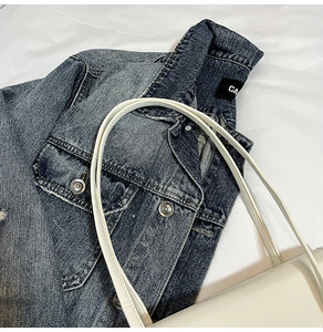 Close-up of a white minimalist large capacity tote bag on a blue denim jacket background