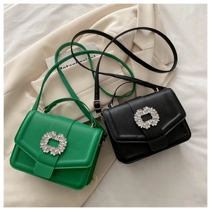 Detail view of emerald green and black pebble leather crossbody bags with rhinestone buckles