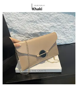 Gros plan sur le sac enveloppe kaki avec chaîne dorée et fermoir métallique rond