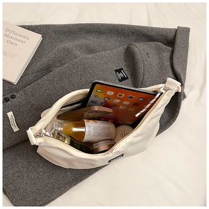 Detail view of spacious nylon tote bag interior holding a tablet, phone, and skincare items