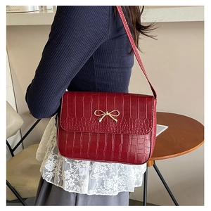 Vue macro de la texture cuir croco rouge foncé et boucle noeud doré sur le sac à main