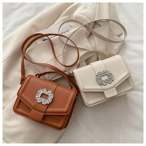 Detail of structured leather handbags featuring large round crystal buckles in brown and beige