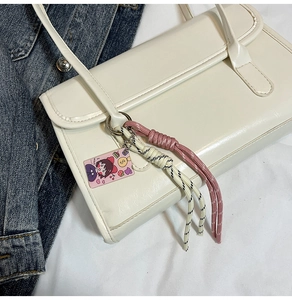 Detail of white PU leather rectangular handbag with colorful braided rope and character tag