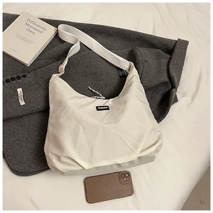 Detail of minimalist beige nylon hobo bag featuring a central black FASHION label