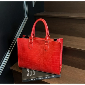 Macro view of bright red faux leather tote bag showing detailed crocodile pattern texture
