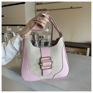 Detail view of pink and beige patchwork fabric shoulder bag with golden buckle accents