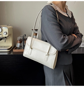 Detail of a creamy white rectangular faux leather underarm bag with slim straps