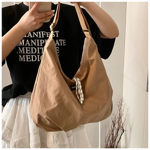 Detail of khaki nylon tote bag with adjustable strap and Fashion patch on a model