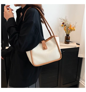 Detail of contrast color tote bag featuring brown leather trim and retro buckle closure