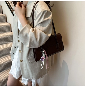 Detailed view of deep brown vintage shoulder bag with matte finish and woven charm pendant
