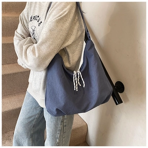 Detail of navy nylon hobo bag featuring decorative woven cords and wide shoulder strap