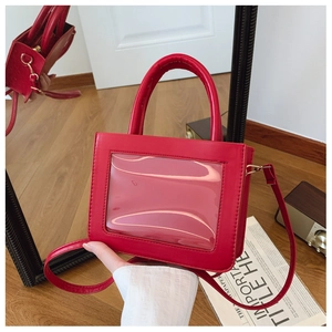 Macro shot of red PVC square crossbody bag featuring a clear front window and top handle