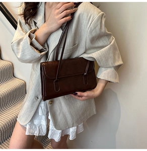 Dark brown faux leather shoulder bag styled with a beige blazer and white lace dress