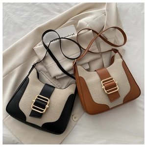 Detail view of vintage canvas underarm bag with leather trim and gold metal buckle