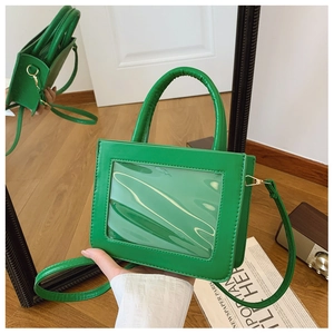 Detail of green PVC handbag with transparent window and circular handle on mirror