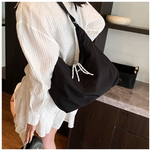 Detail of black nylon tote bag featuring white fashion drawstring ties on white dress