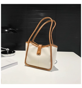 Minimalist beige leather tote bag with brown trim on a desk with elegant props