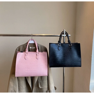 Detail of pink and black tote bags with embossed crocodile texture and sturdy handles