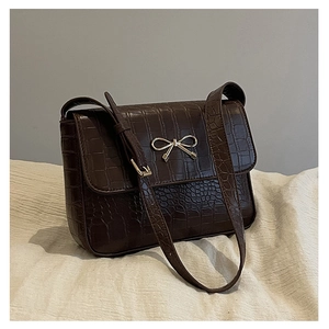 Détail du sac marron foncé à texture crocodile avec nœud doré métallique décoré