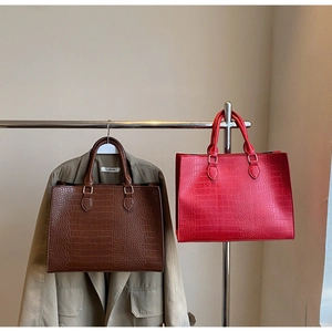 Detail showing crocodile texture large tote bags in brown and red on boutique display