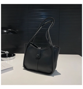 Close-up of the litchi grain texture and buckle detail on this black tote bag