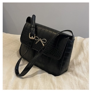 Détail de la texture crocodile sur sac bandoulière noir avec nœud métallique