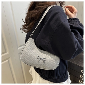 Close-up of silver glitter armpit bag featuring a metallic bow and sleek zipper detail