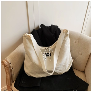 Detailed view of cream-white nylon tote bag with Fashion label on beige sofa