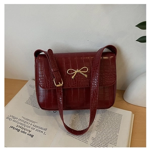 Détail du sac à bandoulière rouge foncé effet croco avec boucle nœud en métal doré
